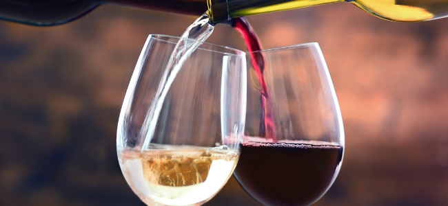 Vino tinto y blanco siendo servidos en copas, mostrando la mezcla de colores y burbujas en el líquido